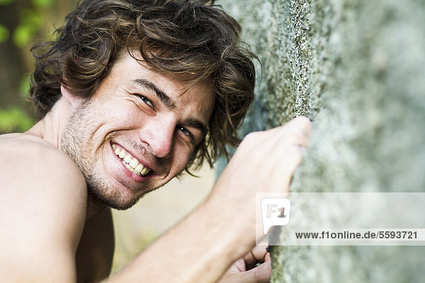 Thailand  Koh Tao  Young man climbing cliff  smiling  portrait