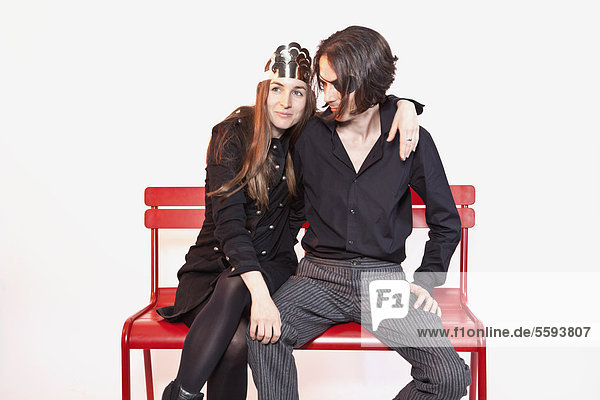 Mittleres erwachsenes Paar sitzt auf einer Bank vor weißem Hintergrund