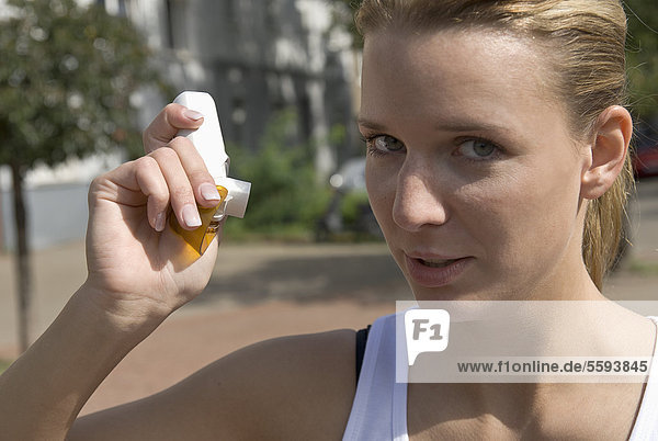 Deutschland  Nordrhein-Westfalen  Düsseldorf  Junge Frau mit Inhalator auf der Straße