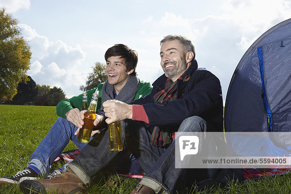 Mann trinkt Bier im Park  lächelnd