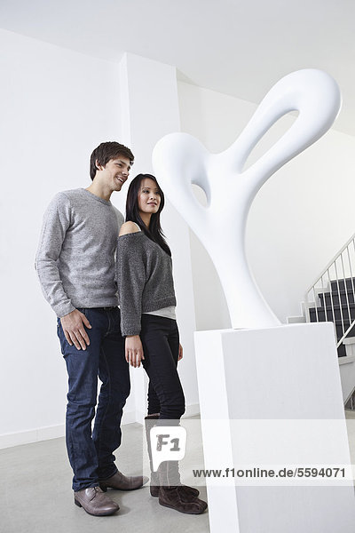 Deutschland  Köln  Junges Paar steht in der Kunstgalerie  lächelnd