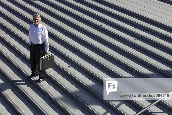 Deutschland  Bayern  München  Geschäftsmann auf Treppe stehend mit Aktentasche  Portrait
