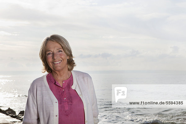 Spain  Mallorca  Senior woman standing at sea shore  smiling  portrait