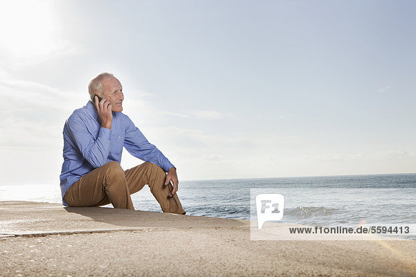 Spanien  Mallorca  Senior Mann auf dem Handy am Meer