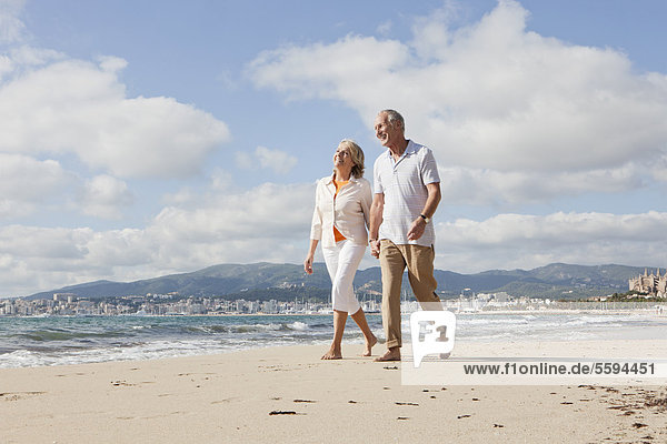 Spain  Mallorca  Senior couple walking along beach  smiling