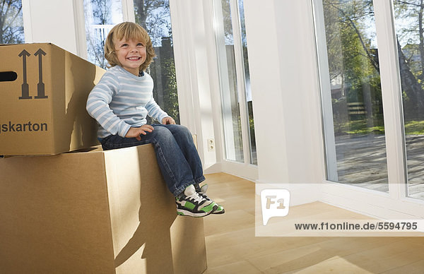 Boy sitting on cardboard box  smiling
