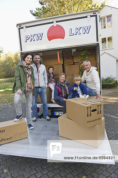 Deutschland  Bayern  Grobenzell  Familie mit Umzugskarton im LKW  lächelnd  Portrait