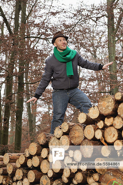 Junger Mann auf einem Holzstapel stehend