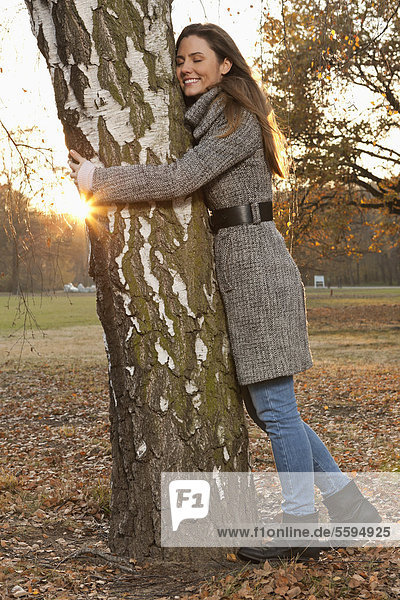 Mid adult woman hugging tree  smiling