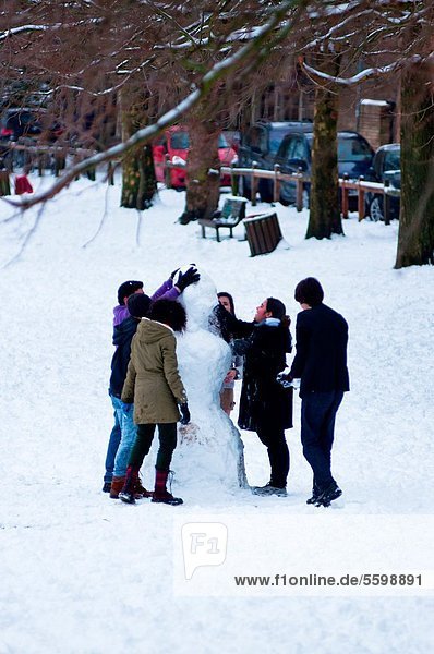 Making a snowman at Parkers Piece in winter  Cambridge  England