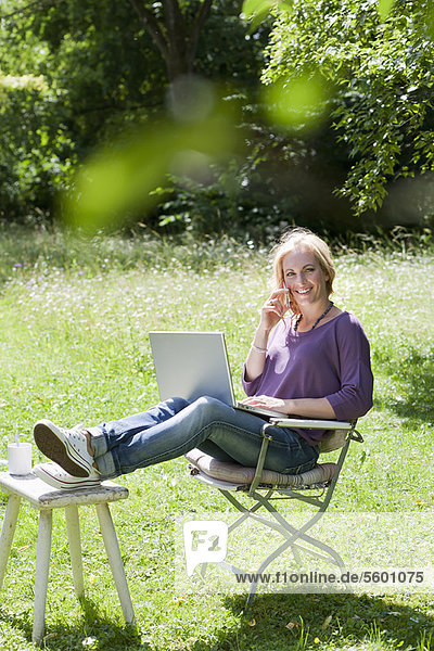 Lächelnde Frau mit Laptop im Freien
