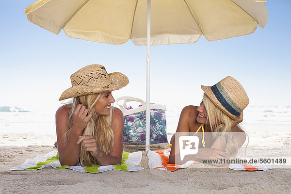 Women relaxing under umbrella on beach