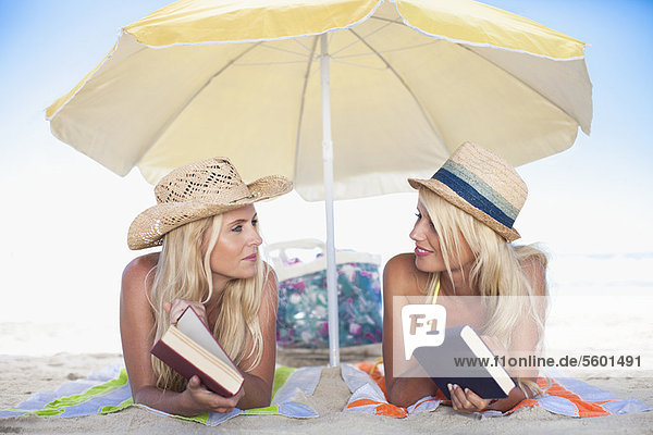 Women relaxing under umbrella on beach