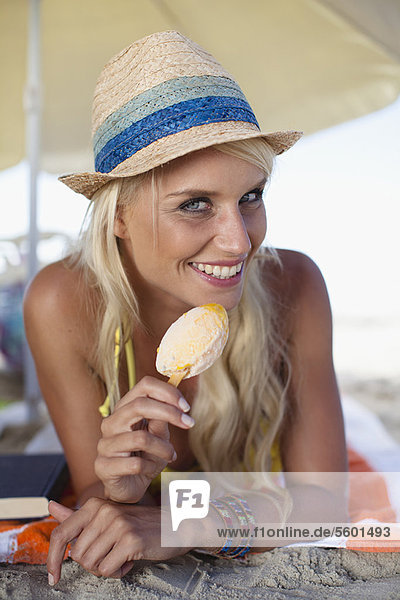 Smiling woman eating popsicle on beach