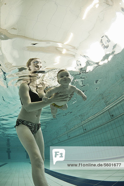 Frau bringt dem Baby das Schwimmen im Pool bei