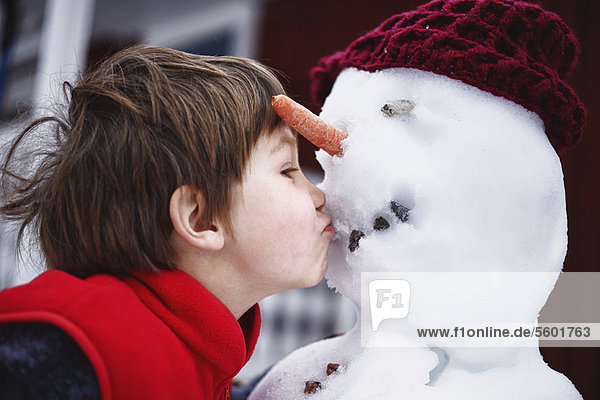 Nahaufnahme des Jungen,  der den Schneemann küsst