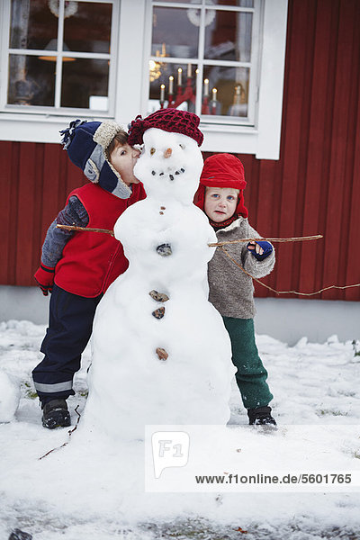 Kinder stehen mit Schneemann