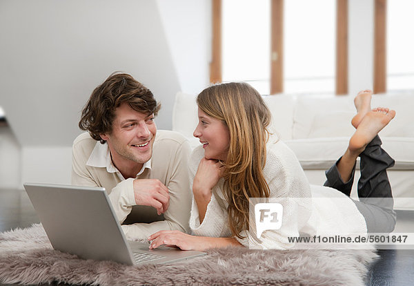 Couple using laptop together on rug