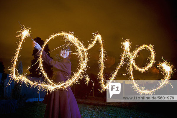 Woman writing LOVE with sparkler