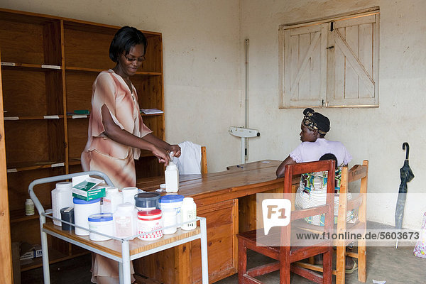 Ärztin in ländlicher Arzneiausgabe gibt Medizin an Patientin aus  Ruanda  Afrika
