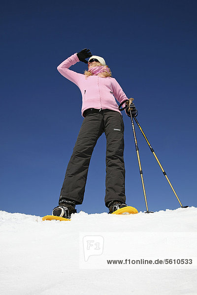 Young woman  about 25 years  snow shoe walking with sticks  against a blue sky  Thuringian Forest mountains  Thuringia  Germany  Europe