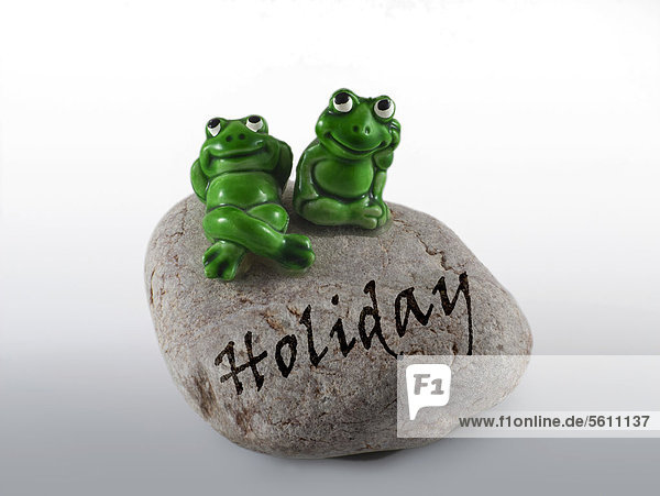 Froschfiguren auf Stein mit Aufschrift Holiday