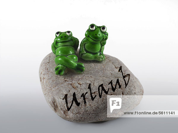 Froschfiguren auf Stein mit Aufschrift Urlaub