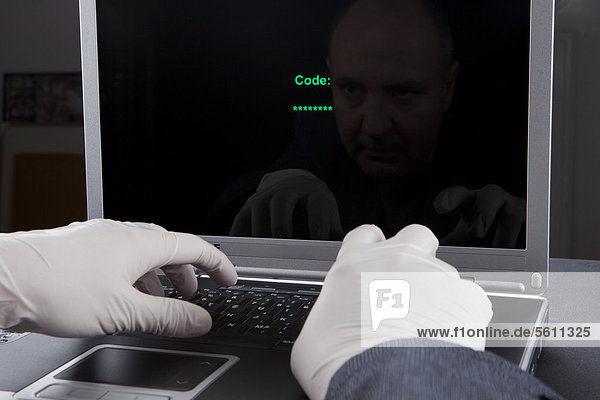 Hacker using a laptop  wearing latex gloves to leave no traces  symbolic image for Internet crime