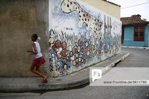 Running girl in front of a painted wall  Camagueey  Cuba  Greater Antilles  Caribbean