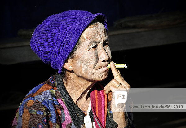 Alte Frau mit Thanaka-Paste im Gesicht und Mütze raucht eine Zigarre  Myanmar  Birma  Südostasien  Asien