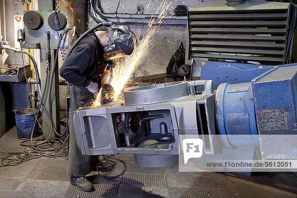 An employee of the Luitpoldhuette AG  a foundry that specializes in the casting of engine blocks  motor parts and refrigeration compressors  trimming a cast rear axle with an angle grinder  in Amberg  Bavaria  Germany  Europe
