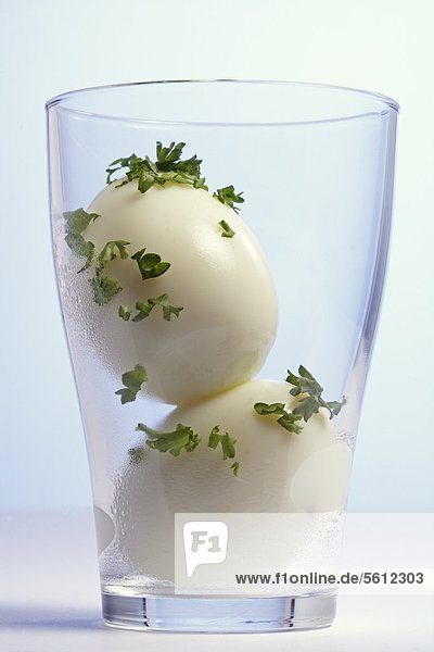 Two boiled eggs with parsley in a glass