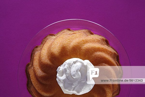 Ring-shaped cake with cream blob on glass plate
