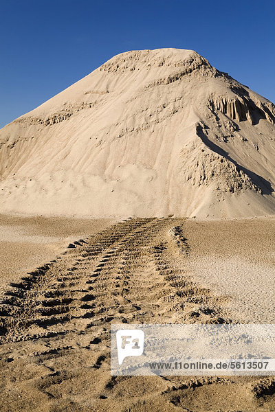 Heavy tire tracks leading to a mound of sand in a commercial sandpit  Quebec  Canada