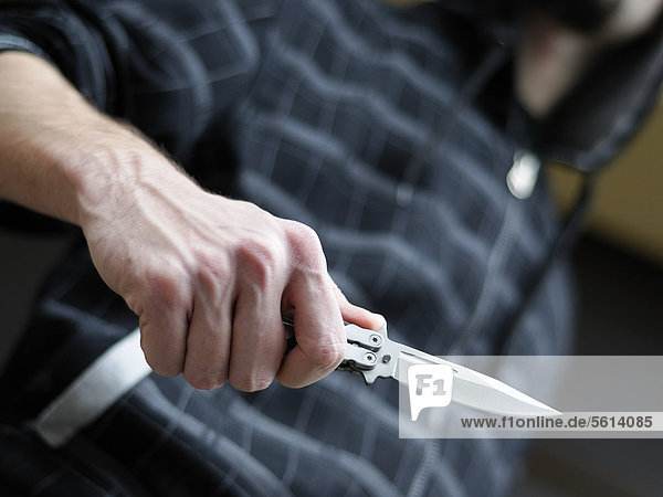 Messerkriminalität  Mann mit Kaputze schwingt ein Butterflymesser  Klappmesser