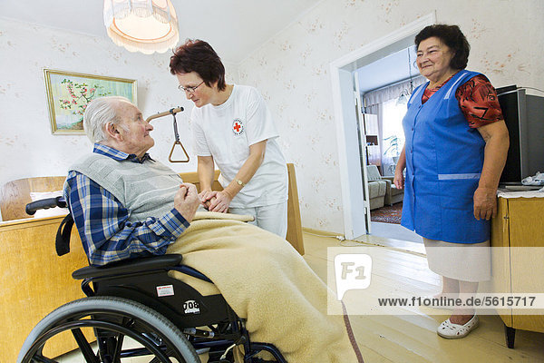 Ambulatory care of the German Red Cross  nurse Anke Lehmann attending an old married couple  as she does every morning  helping the wife to lift her husband with dementia from the bed into a wheelchair  Niemegk  Brandenburg  Germany  Europe