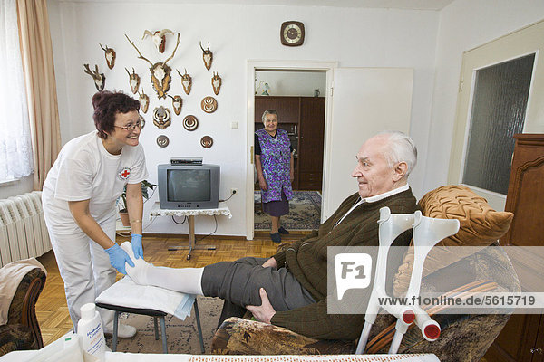 Ambulatory care of the German Red Cross  nurse Anke Lehmann attending an elderly couple  changing the husband's bandage on his foot  Treuenbrietzen  Brandenburg  Germany  Europe