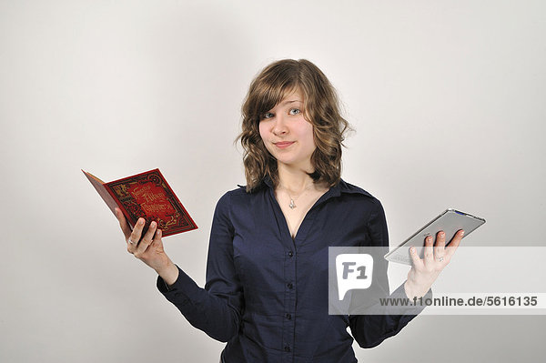 Junge Frau  20 Jahre  mit einem Buch in der einen Hand und einem digitalen Buch  e-book Reader  in der anderen