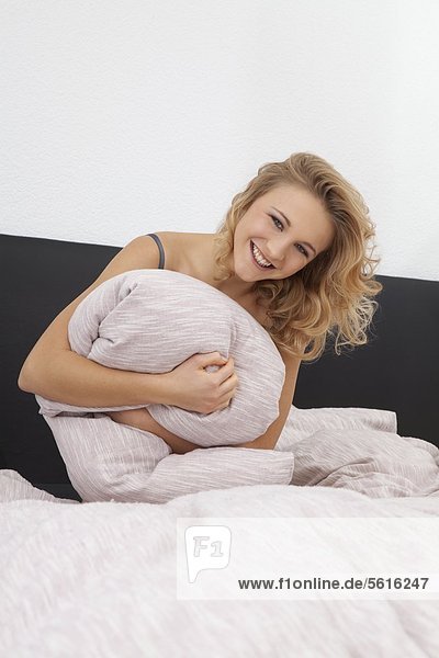 Young woman sitting in bed