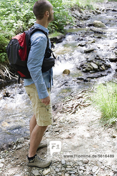 Man hiking along stream in woods