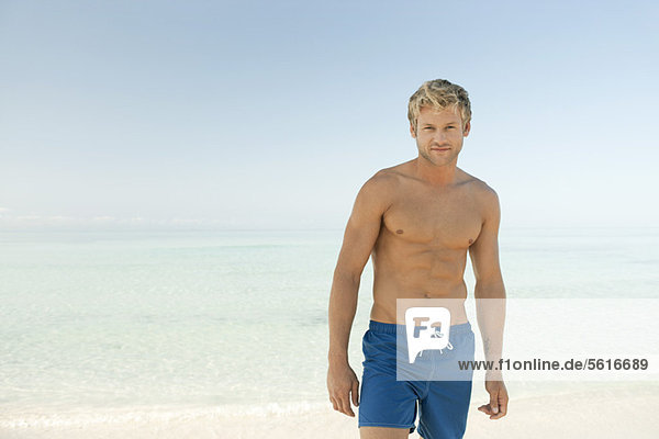 Nackter junger Mann am Strand stehend  Portrait