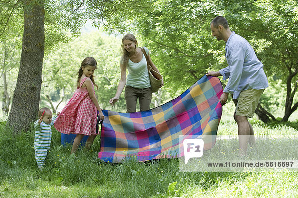 Familie bereitet sich auf ein Picknick auf der Wiese vor