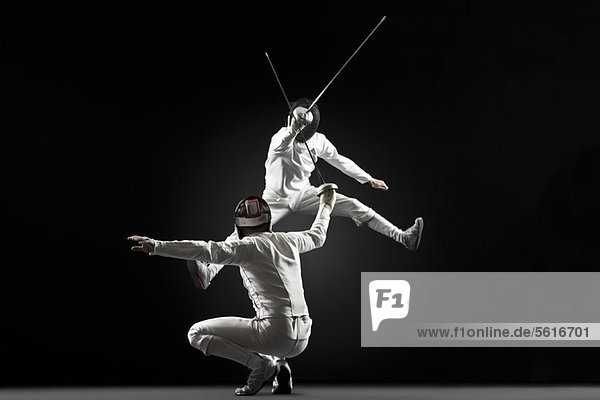 Fencers fencing  one fencer jumping in air