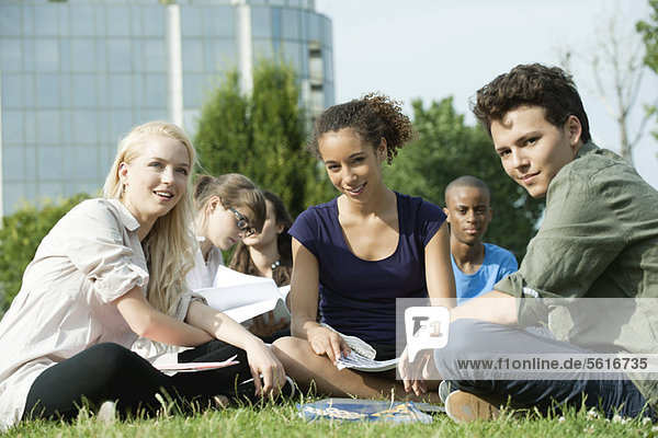 Universitätsstudenten  die gemeinsam auf Rasen studieren  konzentrieren sich auf eine Frau.