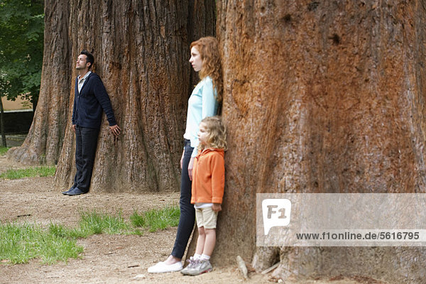 Vater lehnt im Hintergrund an Baumstamm  Frau und Tochter getrennt im Vordergrund