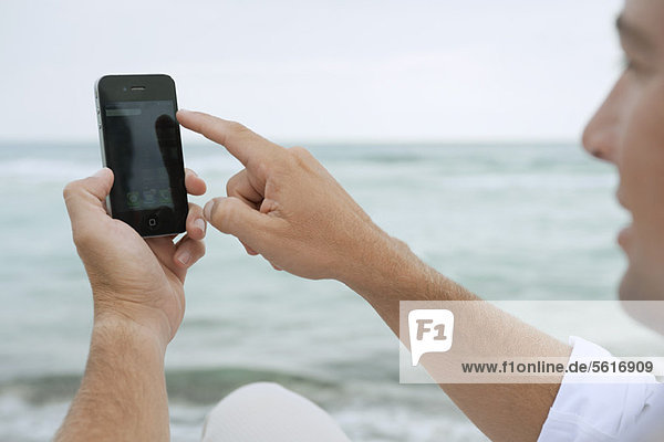 Mann mit Smartphone am Strand
