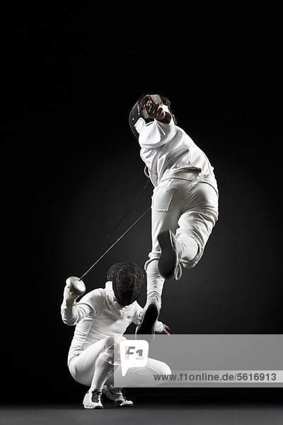 Fencers fencing  one fencer jumping in air