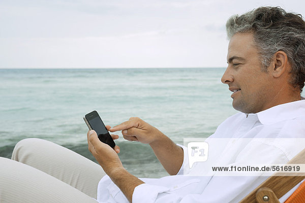 Mann mit Smartphone am Strand