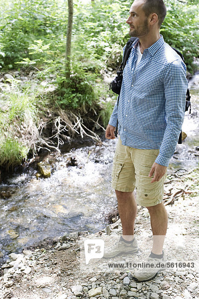Man hiking along stream in woods