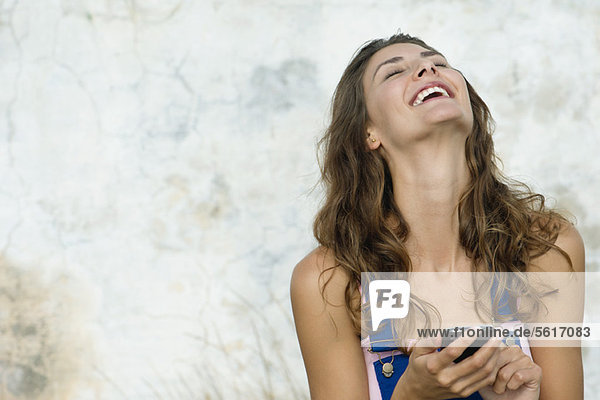 Young woman holding cell phone  laughing